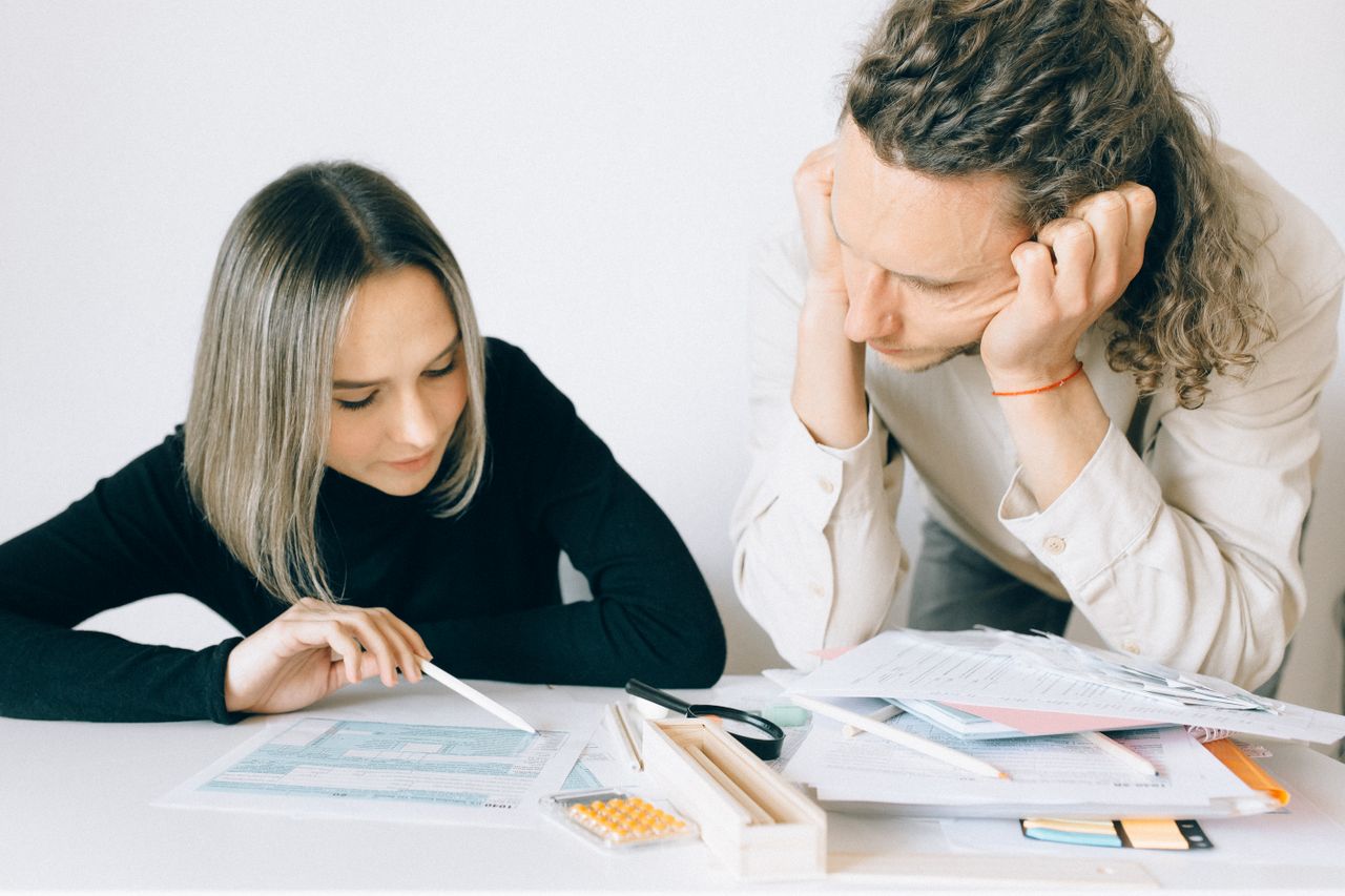 Two colleagues discussing paperwork in a modern office setting.